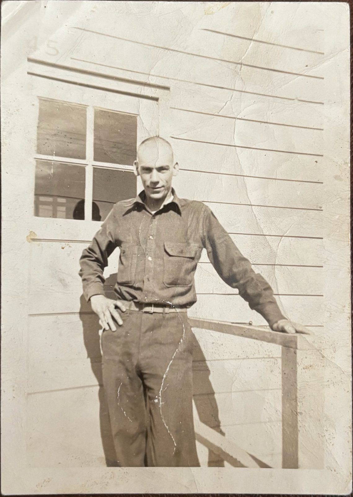 George — with a freshly shaved head — leaning on the rail of barracks '45.'