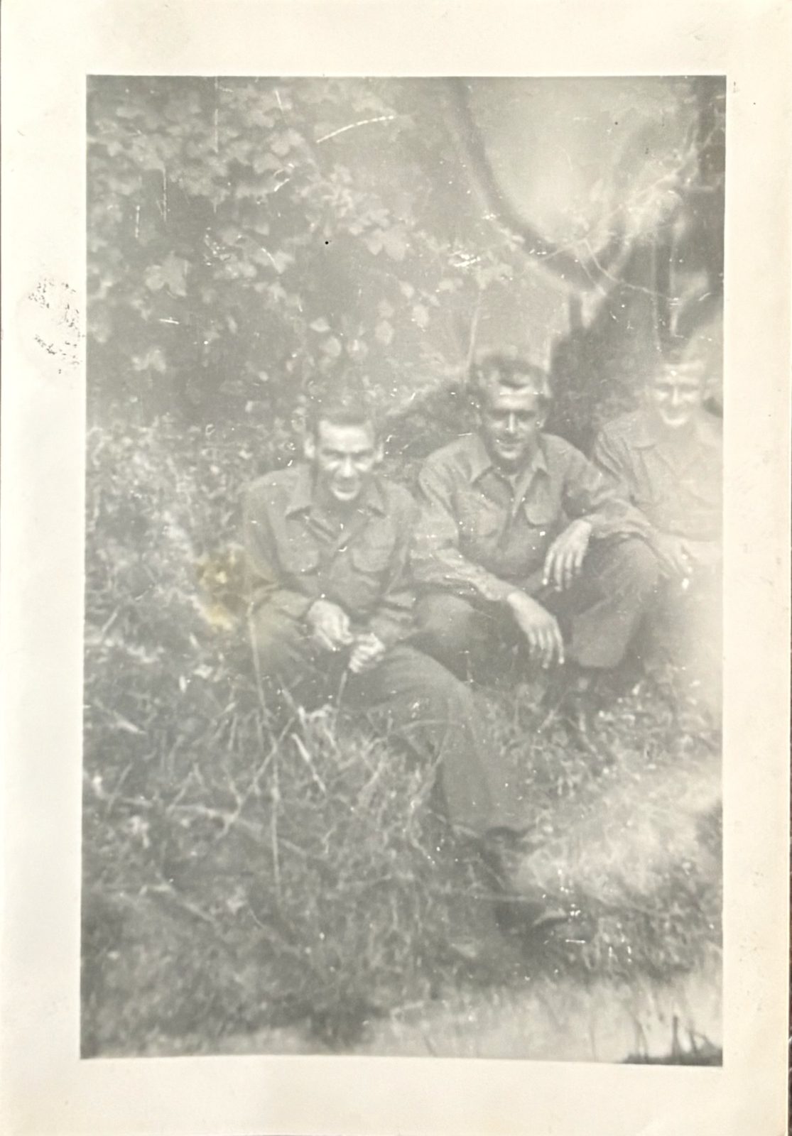 Three soldiers under leafy ivy (faded print) — summer foliage, overseas.